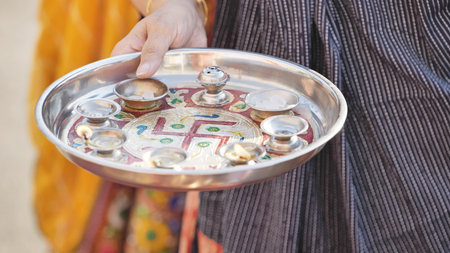 Hand holding puja thali celebrating Ganesh Chaturthi with swastika symbol