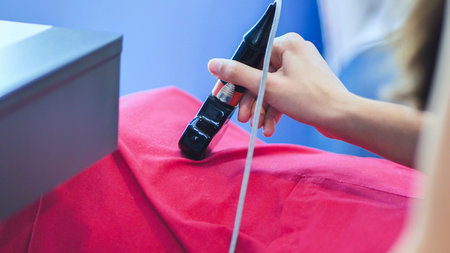 Hand holding an electrical device performing a procedure on a patient in a clinic