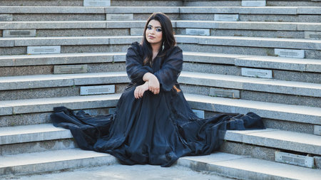 Young Indian woman contemplating while sitting on urban stairs in Moscowの写真素材
