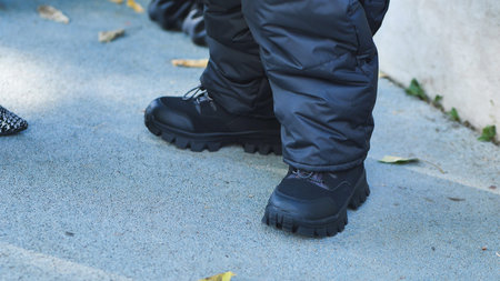 Person wearing black winter boots and puffy pants standing on concrete sidewalk