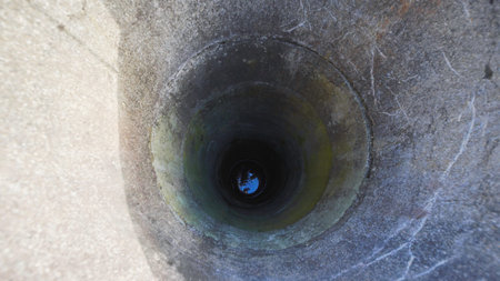 Deep narrow water well with concrete rings reflecting skyの写真素材