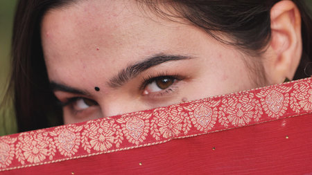 Moscow, Russia - August 25, 2025: Young woman covering face with red sari during India Day cultural...