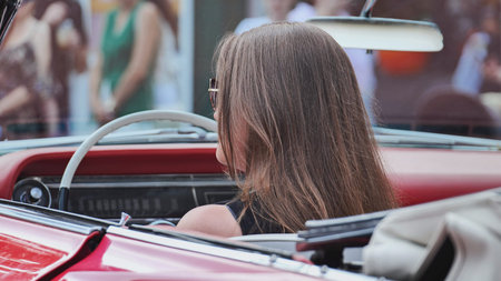 Moscow, Russia - July 5, 2025: Stylish woman driving red convertible car enjoying summer ride