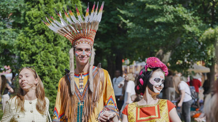 Moscow, Russia - July 5, 2025: Young man in a war bonnet and a woman with sugar skull makeup at an...
