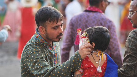 Delhi, India - September 19, 2025: Indian father helping daughter dressing up during Ganesh...