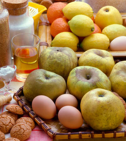 Fruits, eggs, macaroons, a glass of white wine, salt, sugar on a table in kitchen.の写真素材