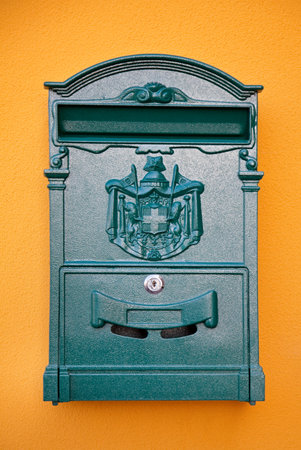 Old green letterbox on yellow wall