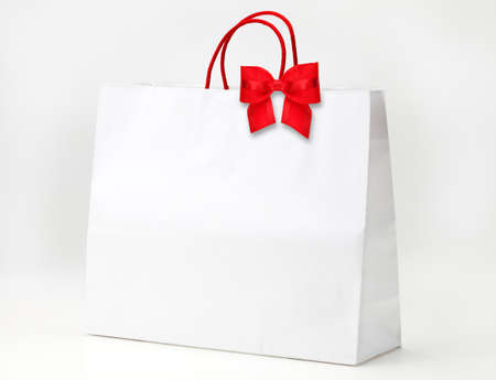 White shopping bag with red bow on white.の写真素材