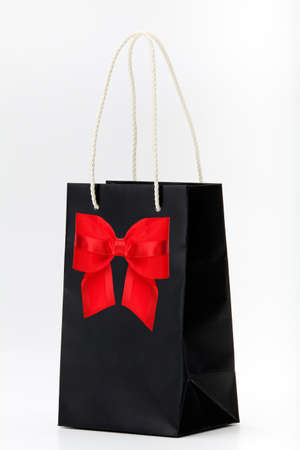 Black shopping bag with red bow  on white の写真素材