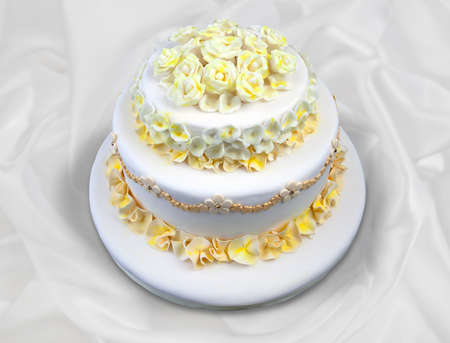 Wedding cake with white and yellow flowers isolated on whiteの写真素材