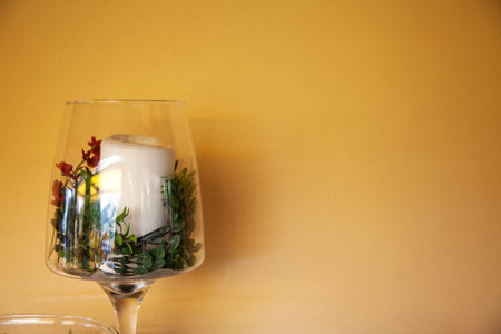 Rustic decor (glass with candle and flower) near yellow wall (with sopace for your text or logo)の写真素材