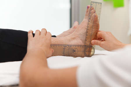 Doctor or physiotherapist measuring active range of motion using manual goniometerの写真素材