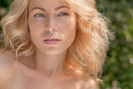 Beautiful young blond woman outdoors. Sunny day. Nature summer background. Outside close-up portrait of beautiful young happy woman with fresh and clean skinの写真素材