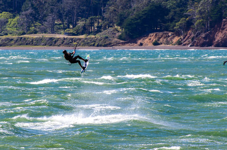 Kite surfer is shown getting some air above the Pacific Ocean near the Golden Gate Bridge with the...