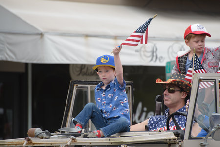 Young Child Waving Flag in float #26 shown in front of Polished in Larkspur California in the Corte Madera Larkspur 4th of July Parade.のeditorial素材