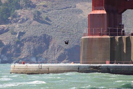 Orange structure of the Golden Gate Bridge and Kite Surfer lifted into the airの写真素材