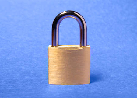 Locked golden padlock on the blue background.の写真素材