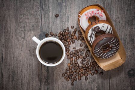 Box of donut with cup of fresh coffee and coffee beans on the wooden tableの写真素材