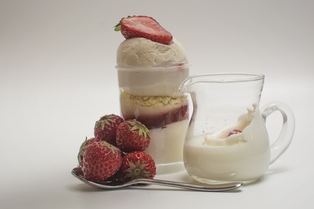 Fresh strawberry falling down to splashing milk near cream desertの写真素材