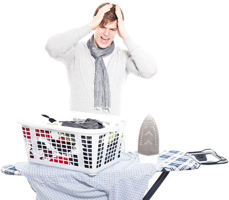 young man completely overwhelmed with his laundry and the electric iron - isolated on white backgroundの写真素材