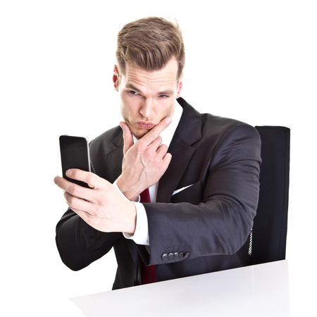 Young businessman taking a selfie with his smartphone - isolated on whiteの写真素材