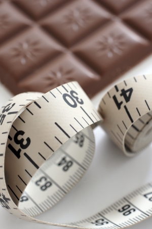 A tape measure with a defocussed chocolate bar in the back ground の写真素材