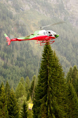 Falcade, Belluno, Italy - August 21, 2015: transport helicopter provides material for a construction site in the mountainsのeditorial素材