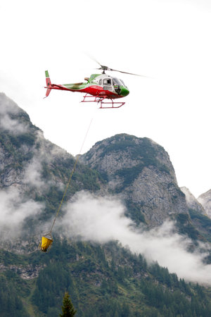 Falcade, Belluno, Italy - August 21, 2015: transport helicopter provides material for a construction site in the mountainsのeditorial素材