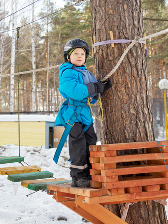 A little boy (6 years old) mountaineering in the winter in a children's rope townの写真素材
