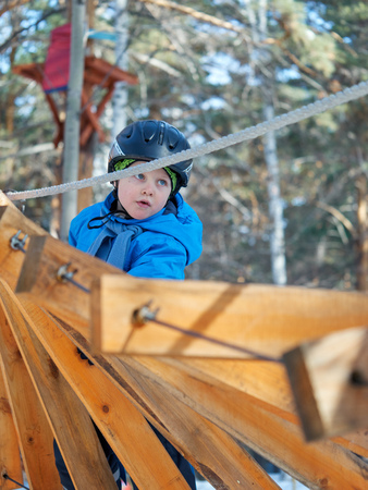 A little boy (6 years old) mountaineering in the winter in a children's rope townの写真素材