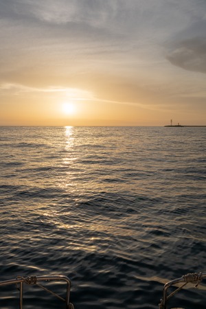 Waves and foam astern of the yacht. The setting sun is beautifully reflected in the water. Background copy spaceの写真素材