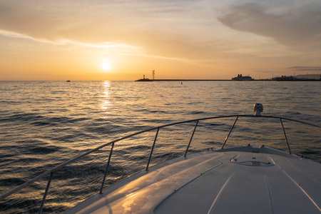 View from the bow of the yacht at orange sunset sun and coastline at the entrance to the port. Background with copy spaceの写真素材