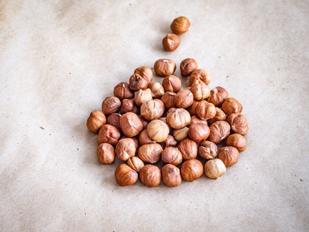 A handful of peeled hazelnut kernels are scattered on coarse craft paper.. Background with copy space.の写真素材