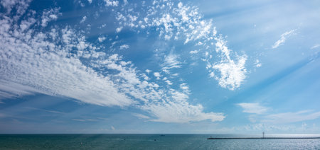 The sky with a little cloudiness over the sea. Breakwater and lighthouse in the sea. Copy space...