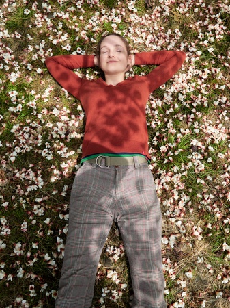 The girl is lying on the grass, strewn with white and pink flowers. The girl is resting on the grass.の写真素材