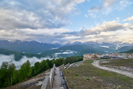 Ski resort in the spring against the backdrop of snowy mountains on a cloudy day. Snowy mountains in the fog. Krasnaya Polyana, Sochi, Russiaの写真素材