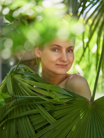The girl hid behind the green palm leaves. Spring colorsの写真素材