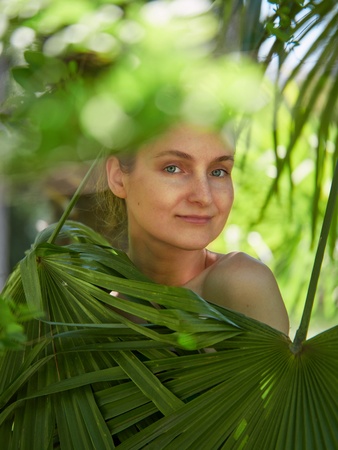 The girl hid behind the green palm leaves. Spring colorsの写真素材