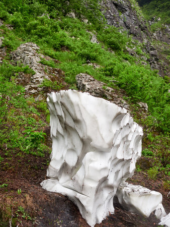 A thick layer of snow melting in the summer in high mountains.の写真素材