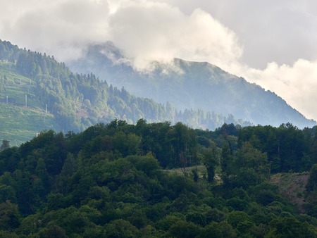 Green mountain slopes in the summer in the clouds. Cable lift on the ski slope in summerの写真素材