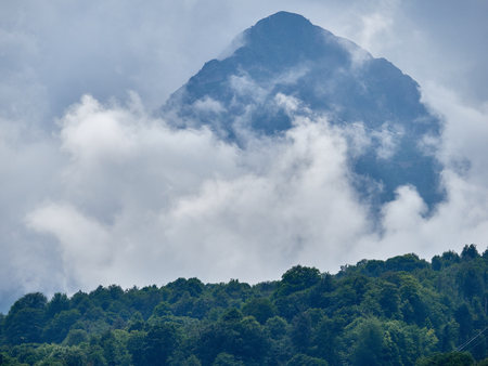 High mountain with green slopes hidden in thick clouds and fog. Black Pyramid Mountain, Krasnaya Polyana, Sochi, Caucasus, Russia.の写真素材