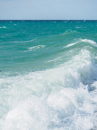 Splashes of water and foam against the sea on a sunny summer day. Copy space backgroundの写真素材