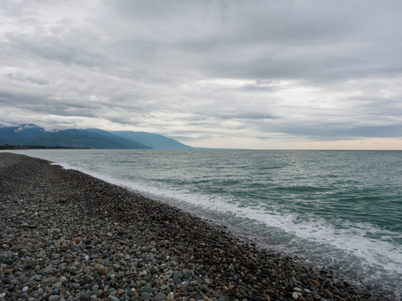 Sea waves on a pebble beach. Sea on a cloudy summer or autumn day.の写真素材
