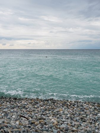 Sea waves on a pebble beach. Sea on a cloudy summer or autumn day.の写真素材