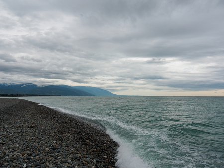 Sea waves on a pebble beach. Sea on a cloudy summer or autumn day.の写真素材
