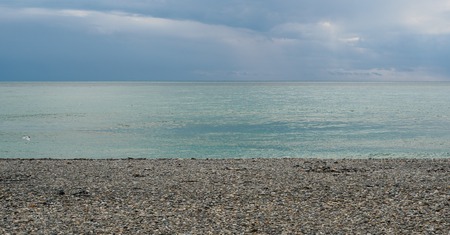 A strip of blue sky and sea over a pebble beach. Seascape in the form of three stripes in the style of minimalism.の写真素材