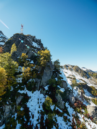 Snowy mountain peak with green and yellow trees. Clear blue sky.の写真素材