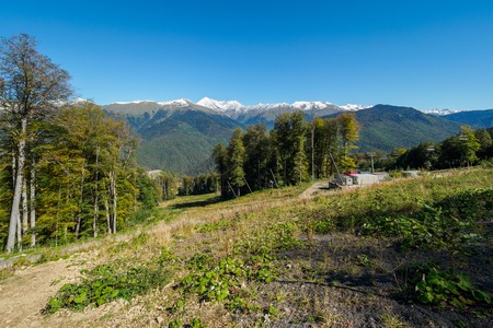 The green slopes of the mountains with snowy peaks and cableways. Mountains in summer or autumn.の写真素材