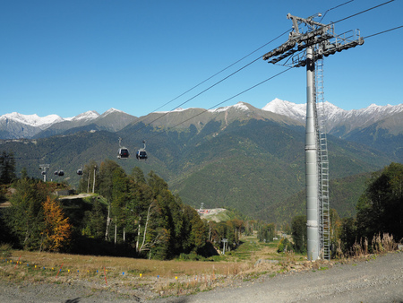 Cableway among the mountains with green slopes and snowy peaksの写真素材