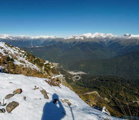 View from the snow-covered mountain range to the green valley in front of him. Krasnaya Polyana,...